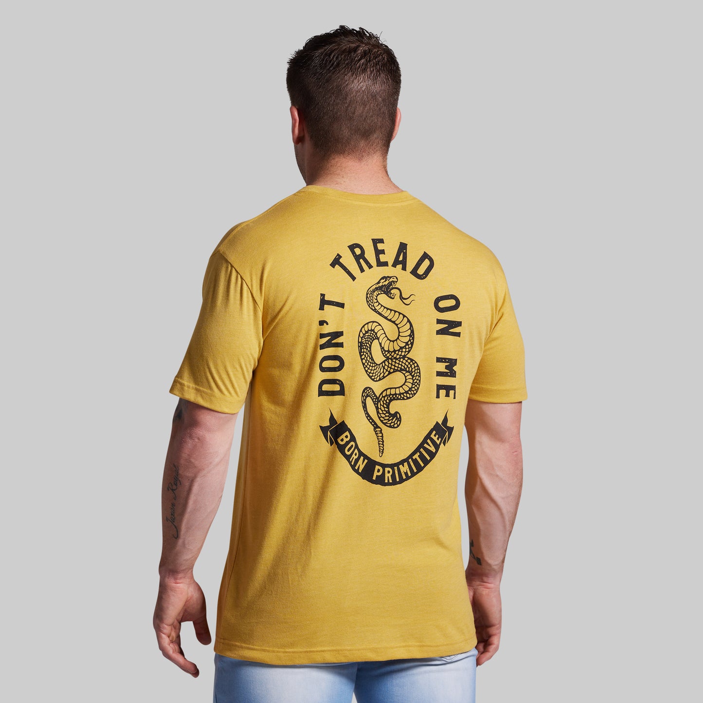 Man wearing a yellow t-shirt with a snake graphic and text on the back against a gray background