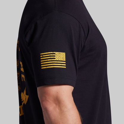 Black t-shirt with yellow flag design on sleeve against a gray background