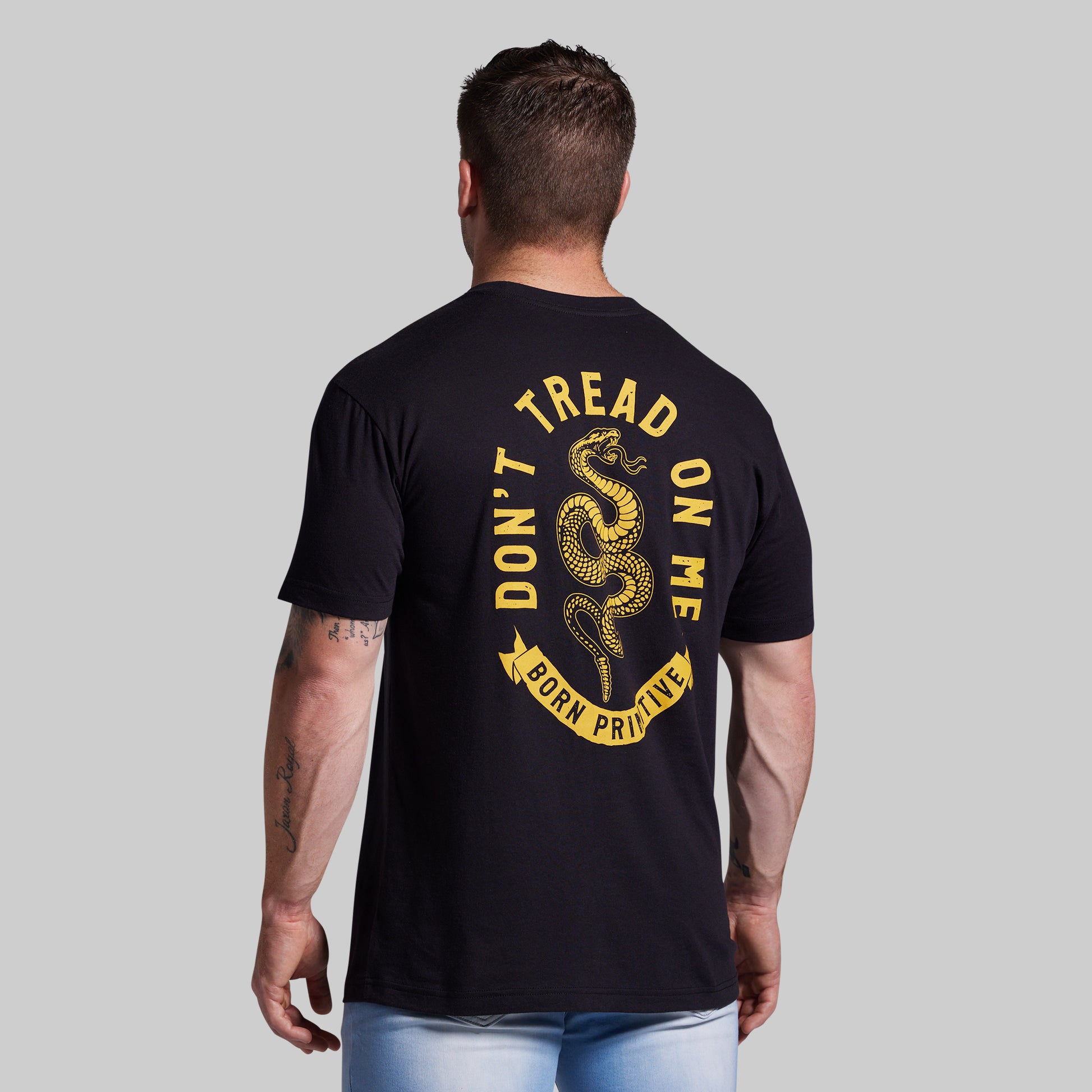 Man wearing a black t-shirt with yellow text and snake graphic on the back, on a gray background