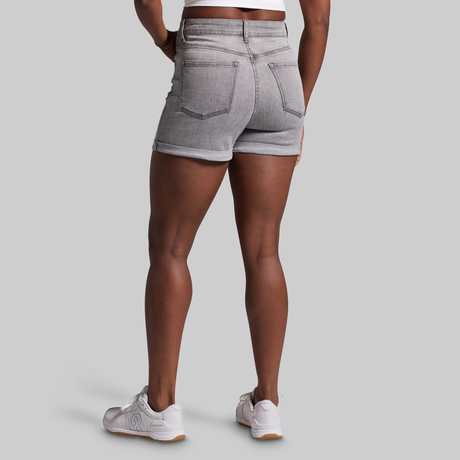 Person wearing gray denim shorts on a plain background