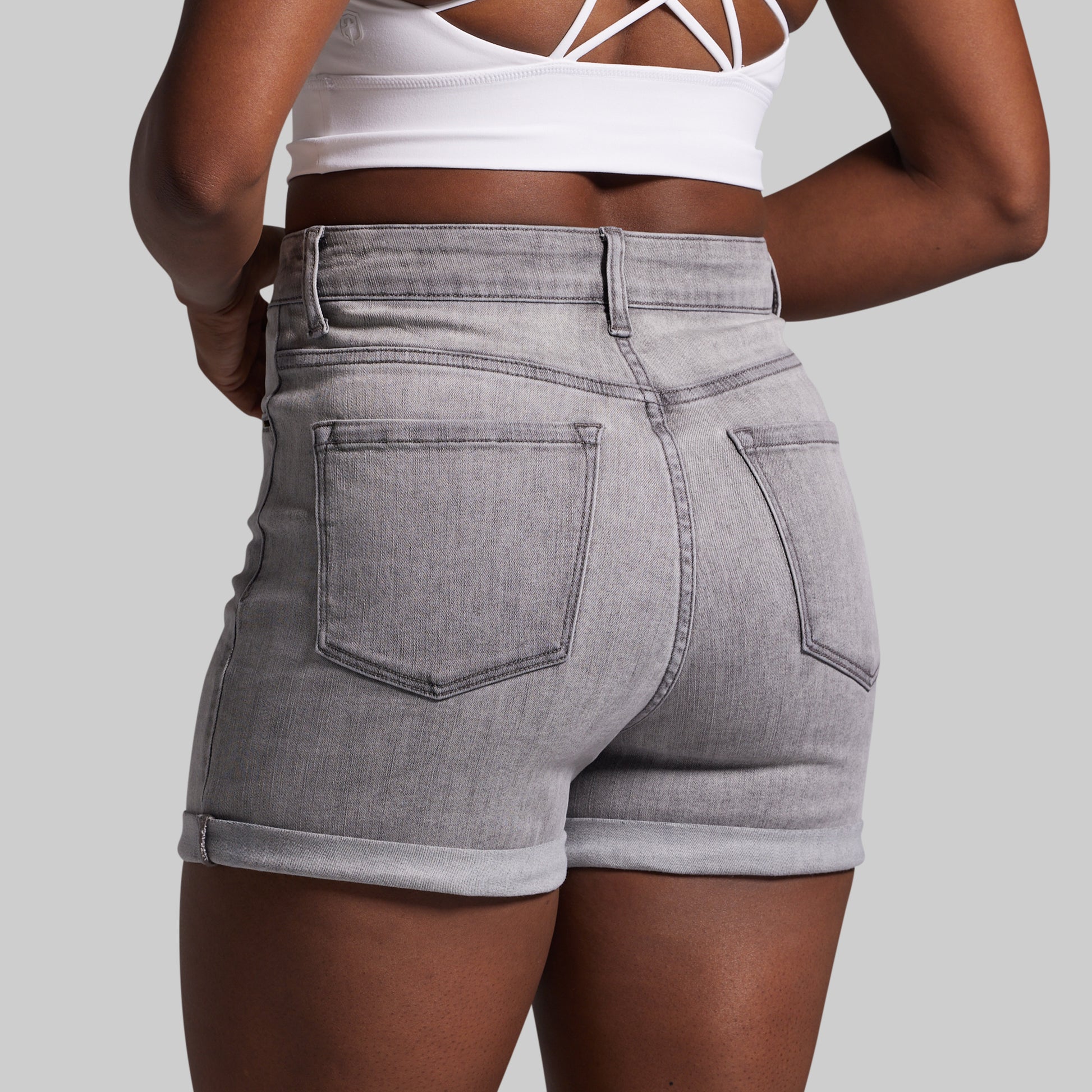 Person wearing gray denim shorts on a plain background