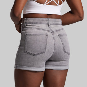 Person wearing gray denim shorts on a plain background