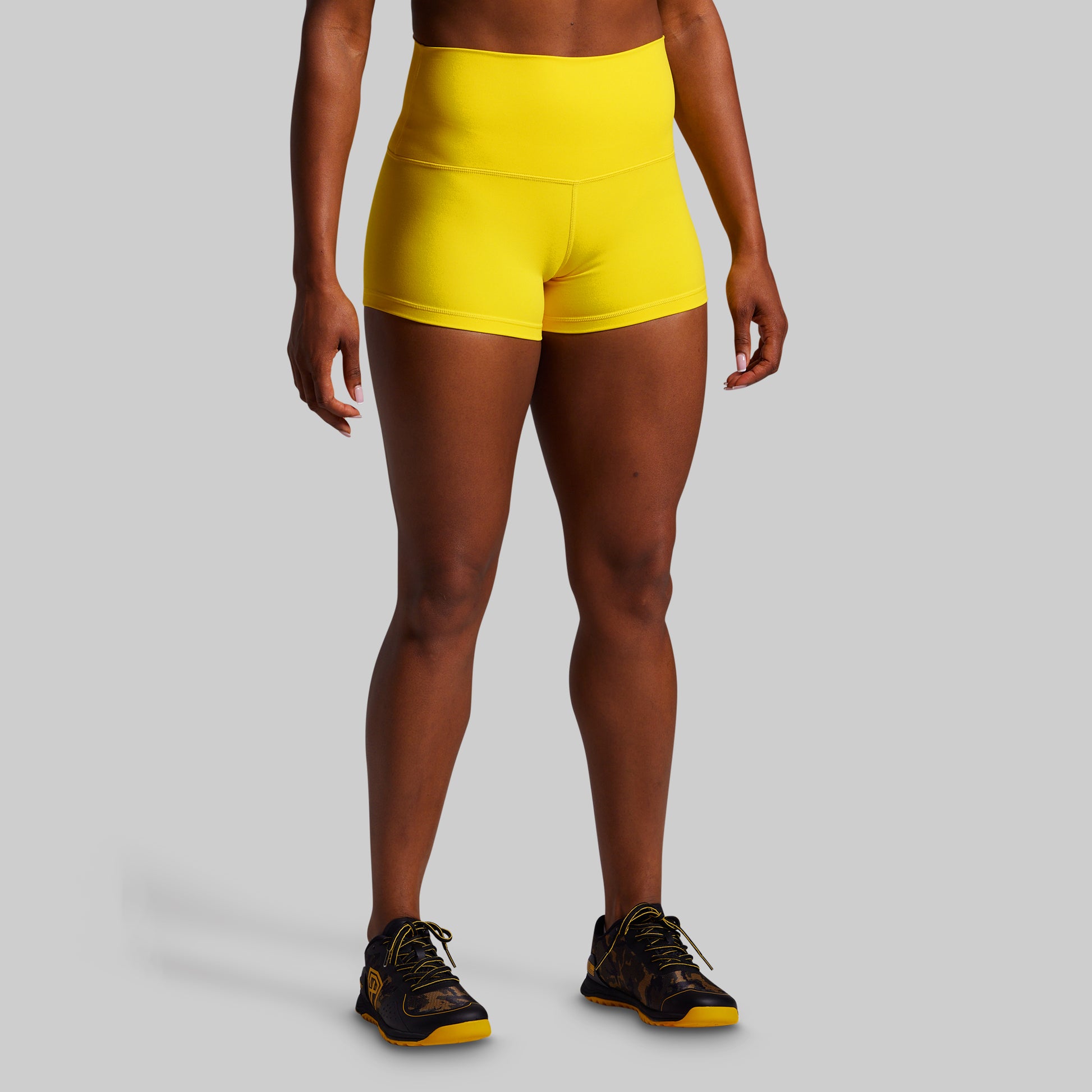 Person wearing bright yellow athletic shorts on a gray background