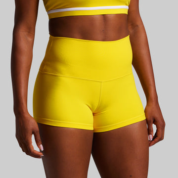 Person wearing bright yellow athletic shorts on a gray background