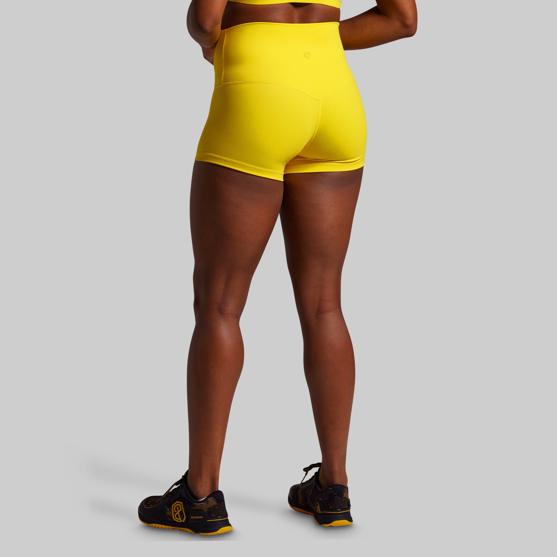 Person wearing bright yellow shorts on a gray background