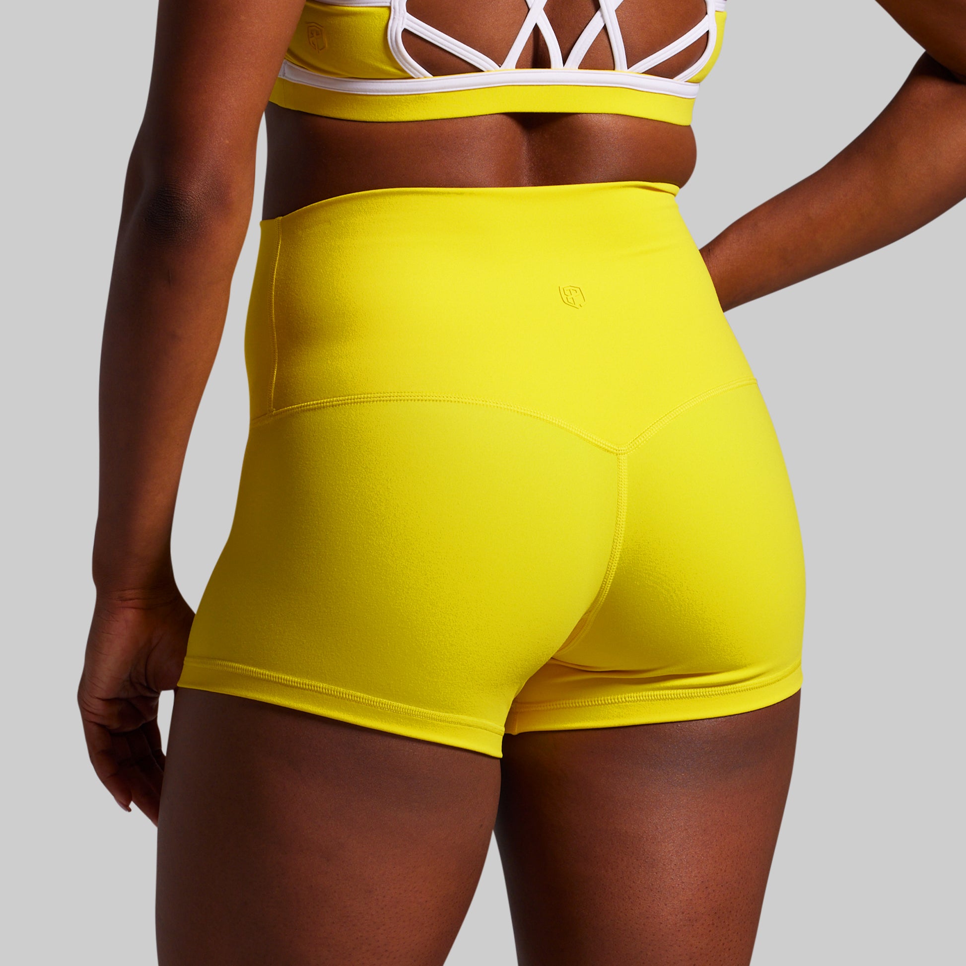 Person wearing bright yellow athletic shorts on a plain background