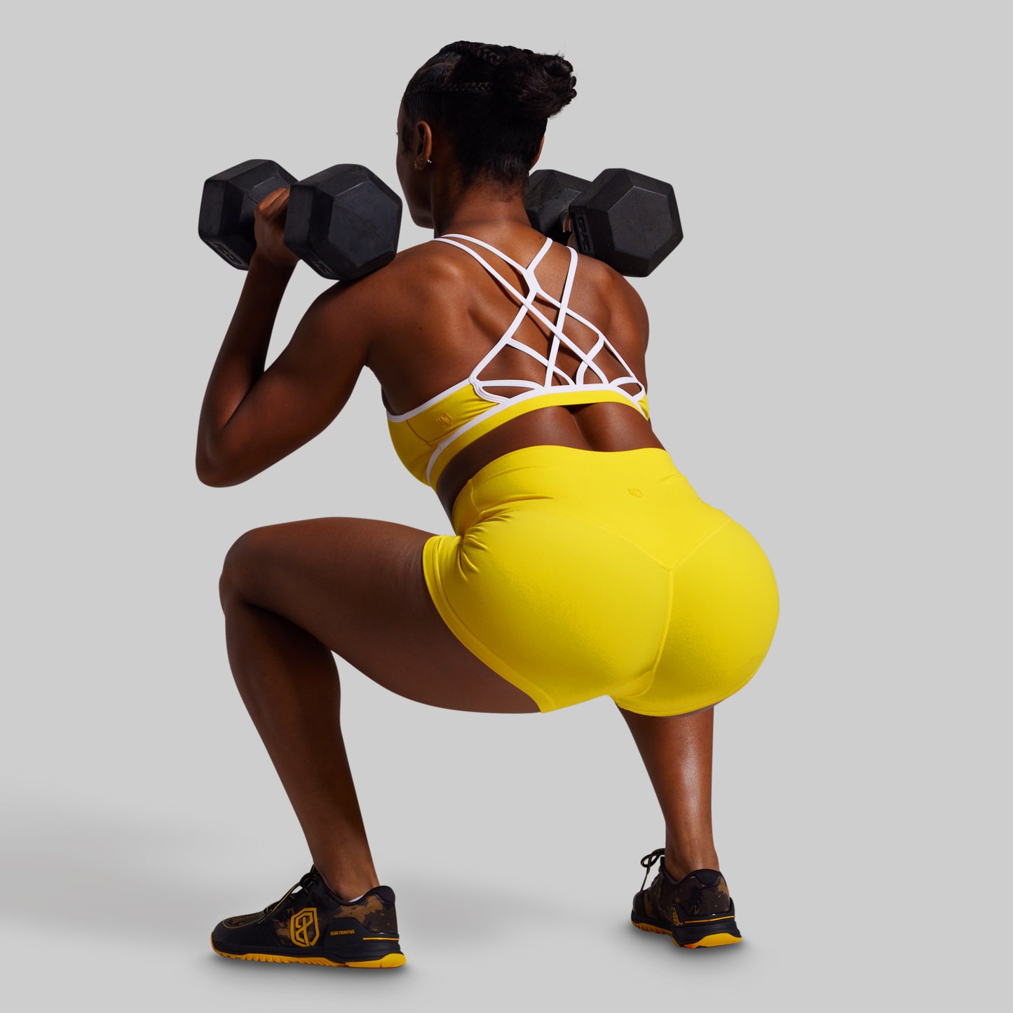 Person in a yellow outfit lifting weights on a plain background