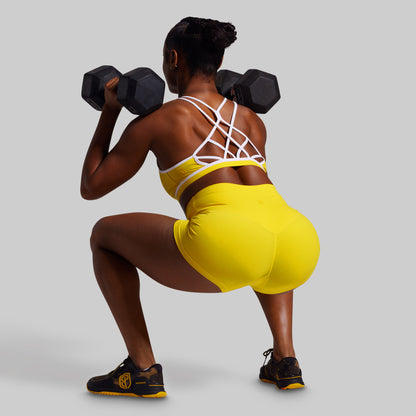 Person in a yellow outfit lifting weights on a plain background