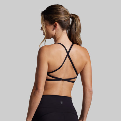 Woman wearing a black strappy sports bra against a gray background