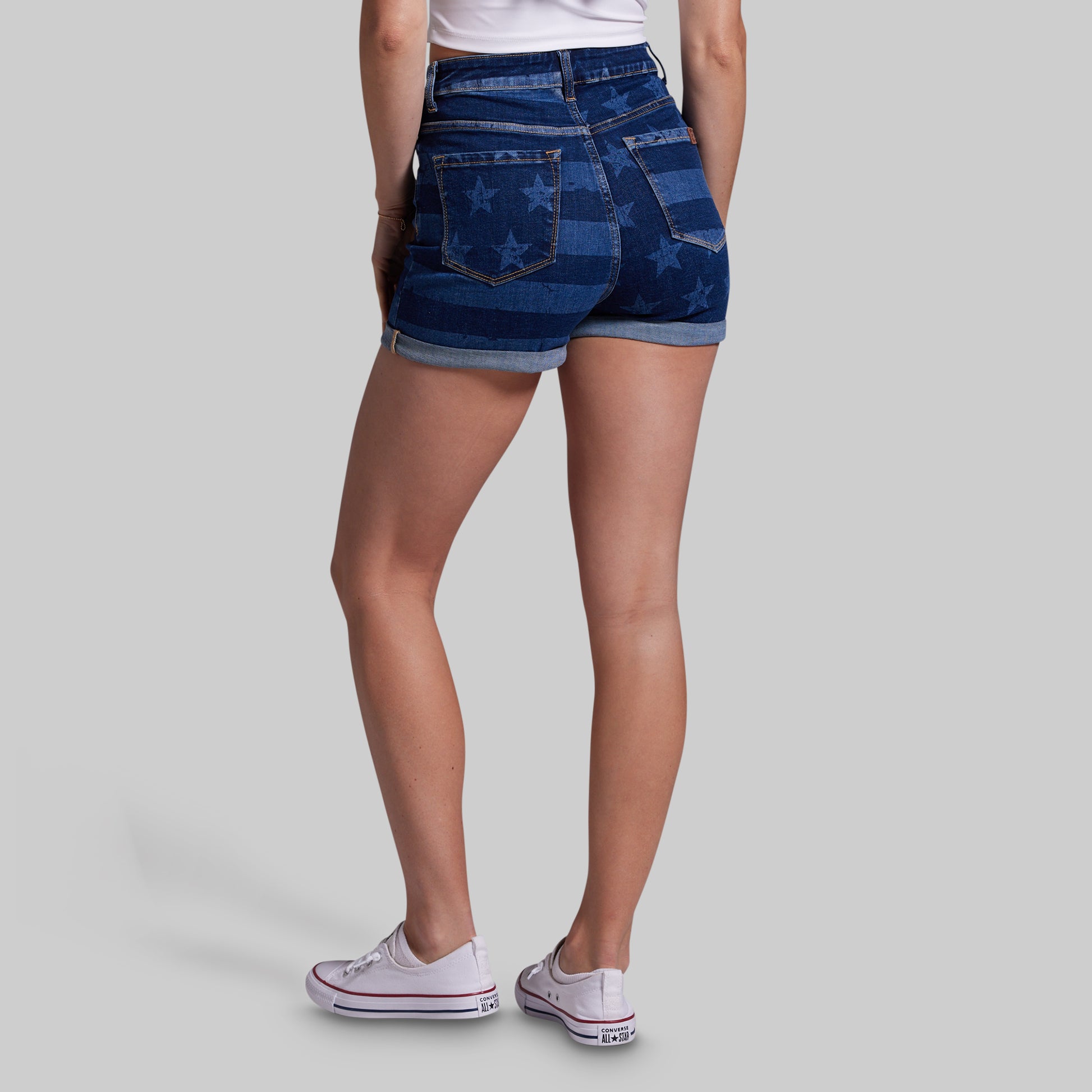 Person wearing blue denim shorts with star pattern on a gray background