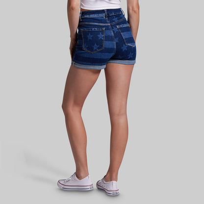 Person wearing blue denim shorts with star pattern on a gray background