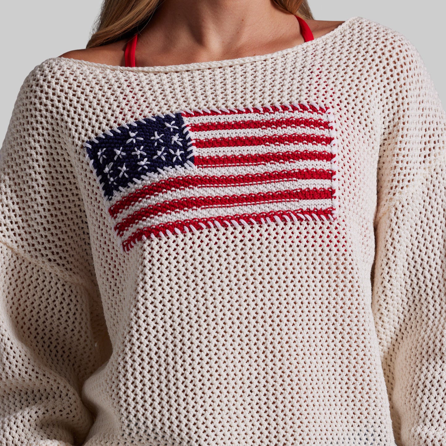 Beige sweater with American flag design on a neutral background