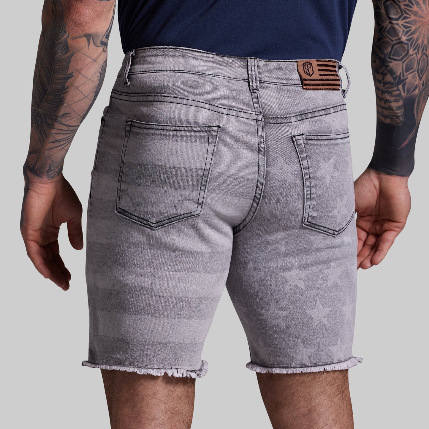 Gray denim shorts with star pattern worn by a person on a plain background