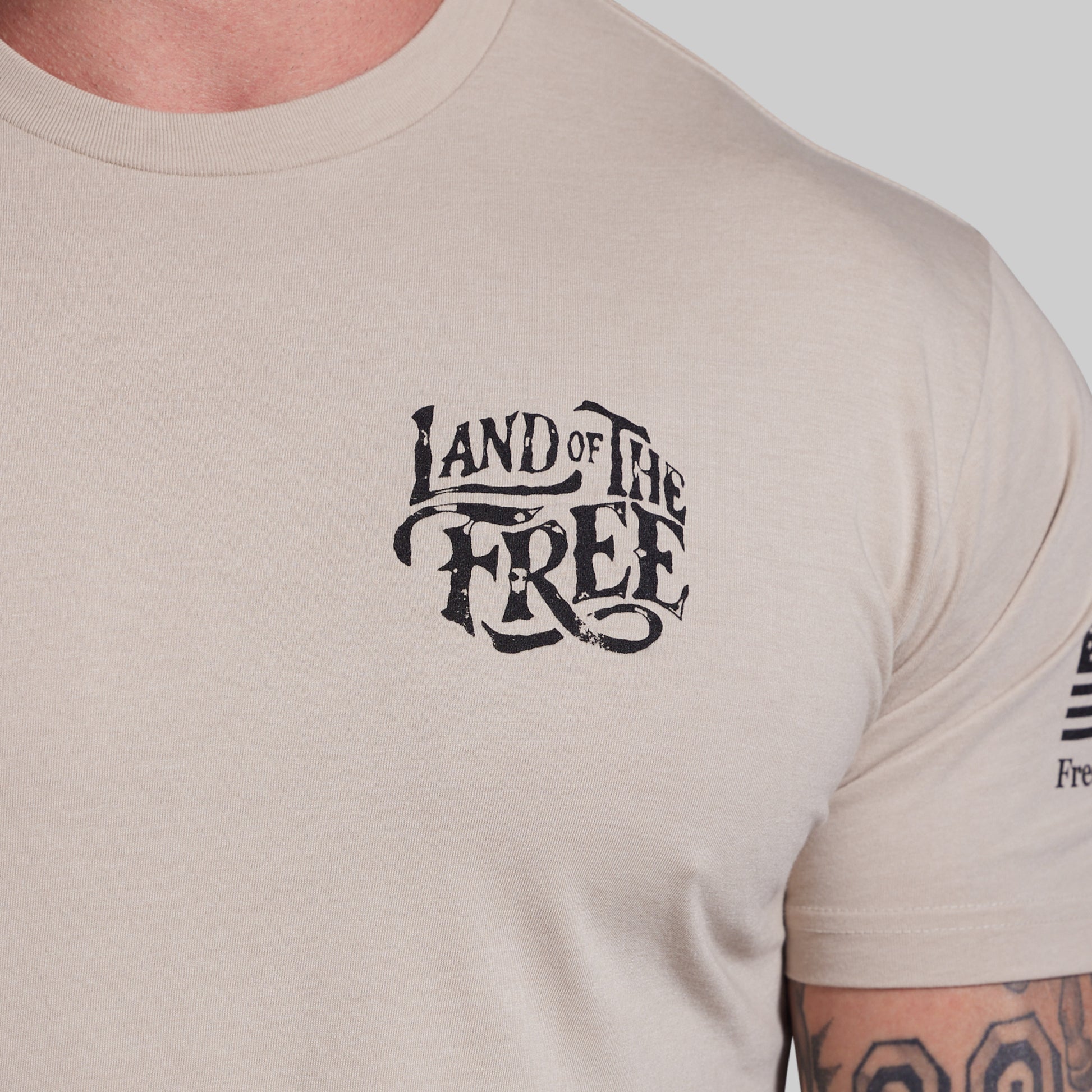 Beige t-shirt with 'Land of the Free' text on a plain background