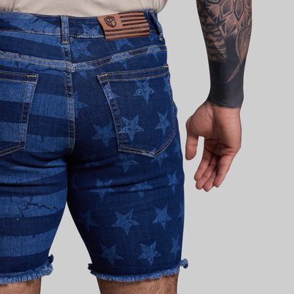 Blue denim shorts with star pattern worn by a person on a gray background