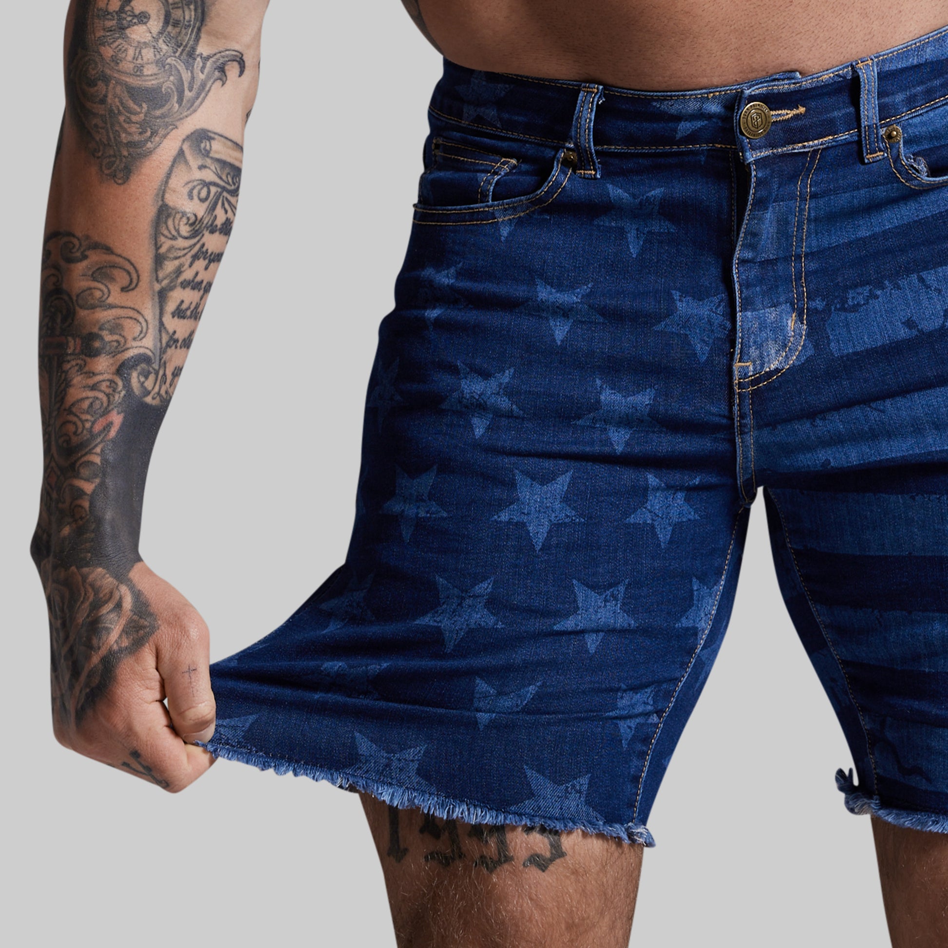Person wearing blue denim shorts with star pattern on a plain background