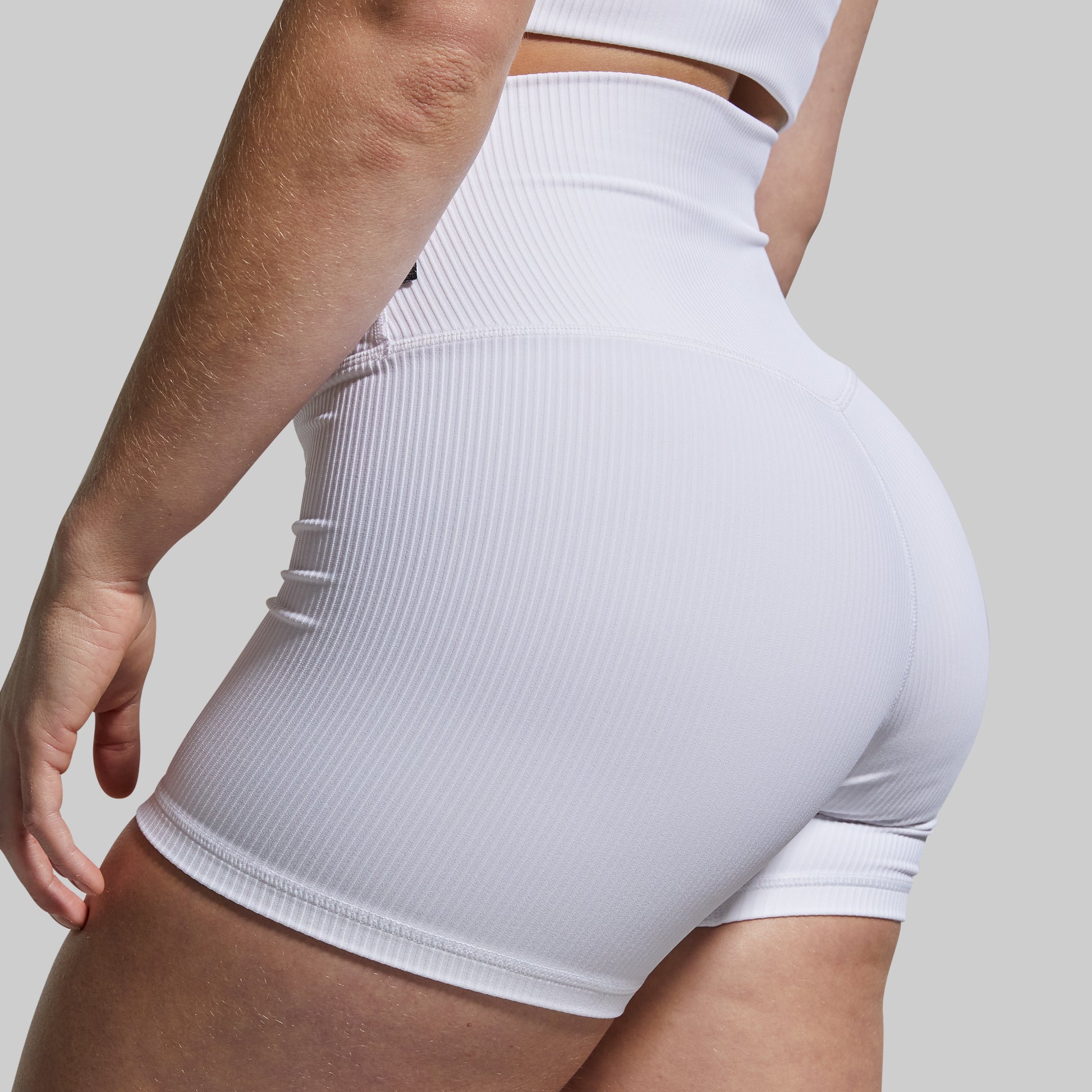 White ribbed high-waisted shorts worn by a person on a light gray background