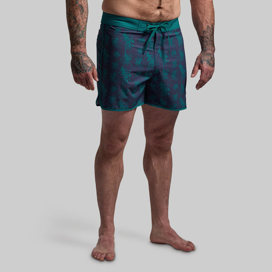 Person wearing teal patterned shorts on a plain background