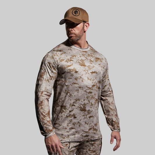 Person wearing a camouflage long-sleeve shirt and pants with a matching cap on a gray background