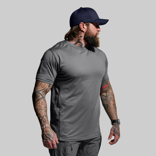 Man wearing a gray t-shirt and navy cap on a light gray background