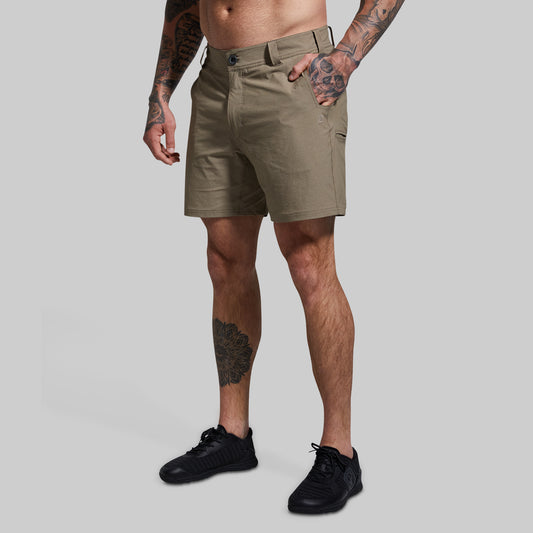 A male model wearing khaki-colored Traverse shorts and black shoes, standing against a white background.