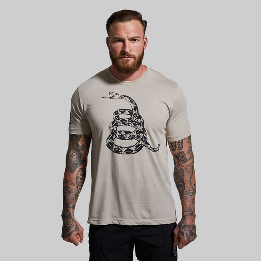 Man wearing a beige t-shirt with a snake graphic design on a plain background
