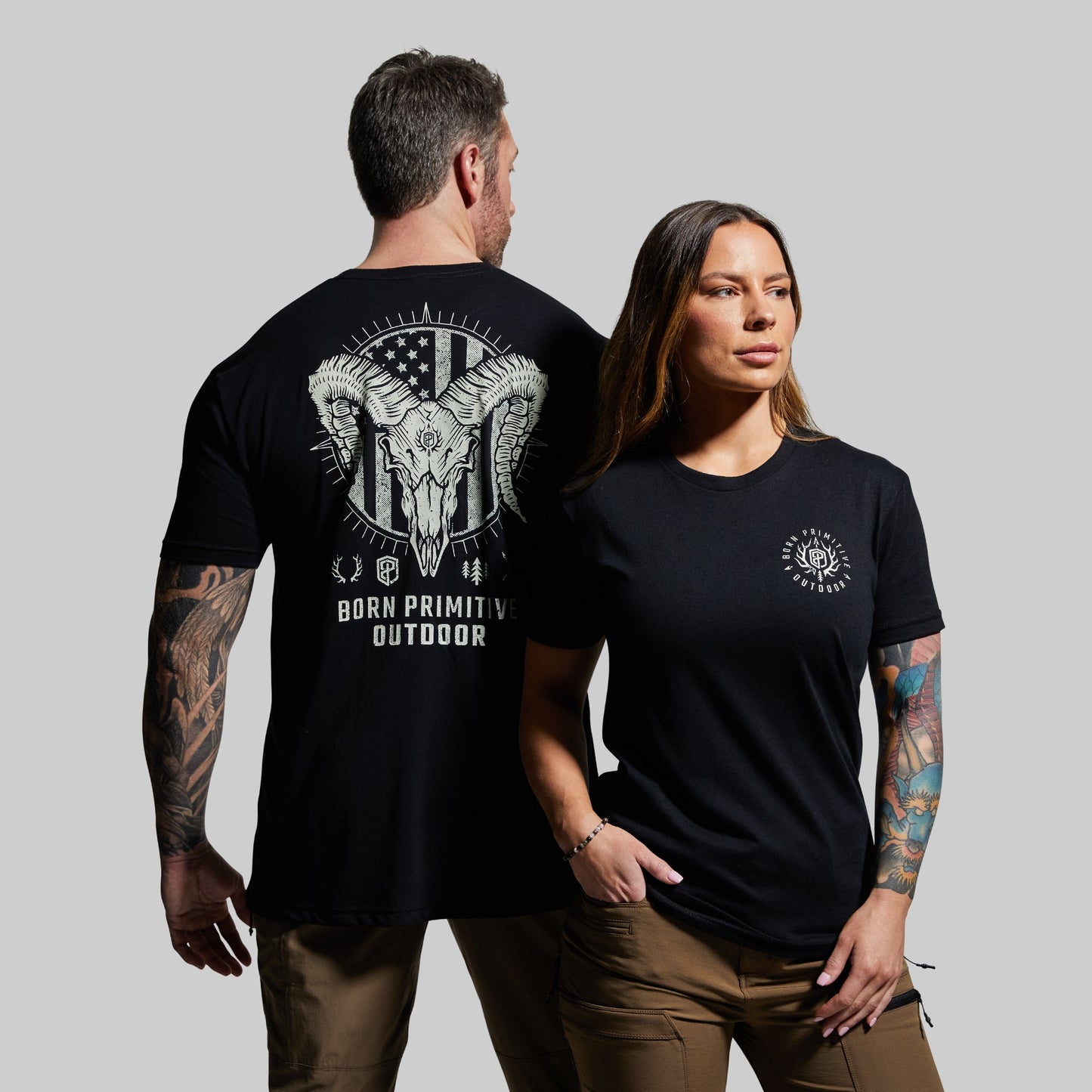 Man and woman wearing black t-shirts with graphic designs on a gray background