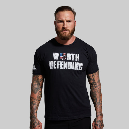 Man wearing a black t-shirt with 'Worth Defending' text on a gray background