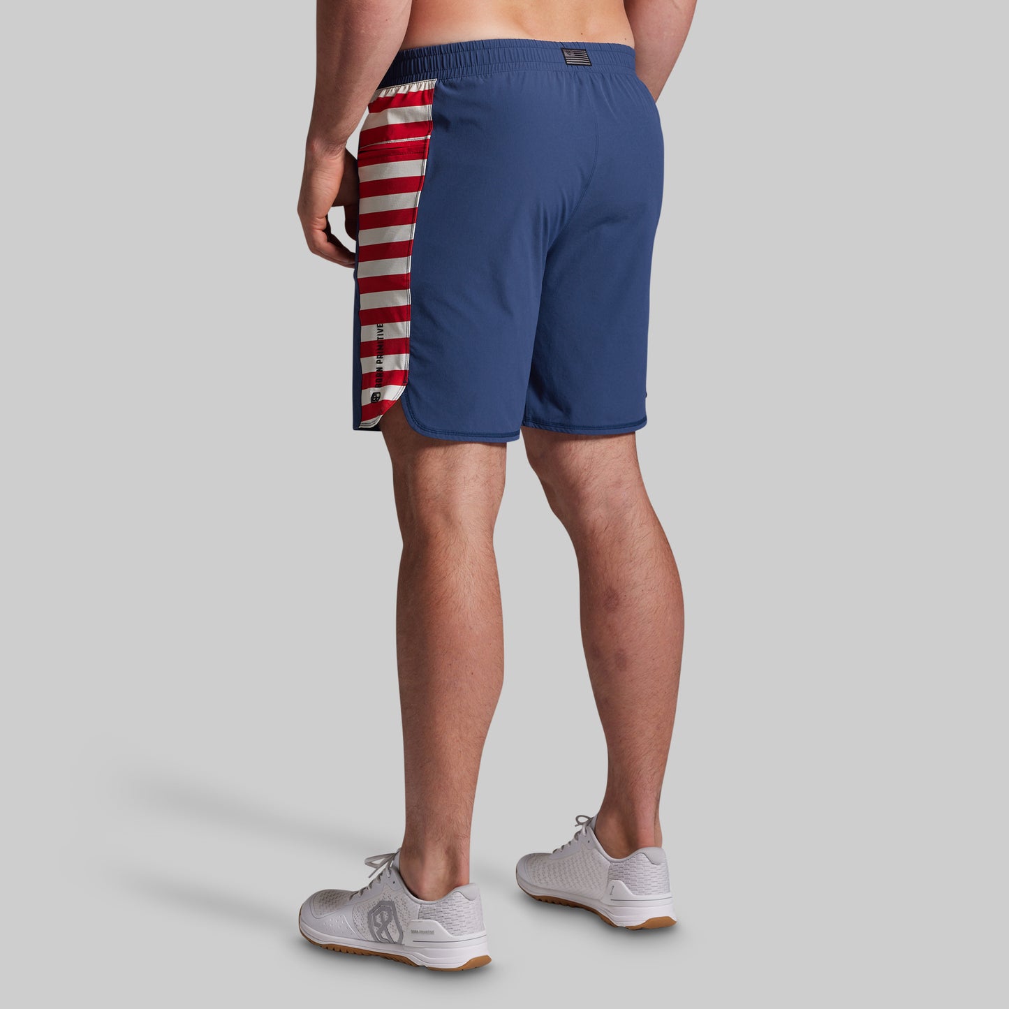 Person wearing blue swim shorts with a red and white striped pattern on a gray background