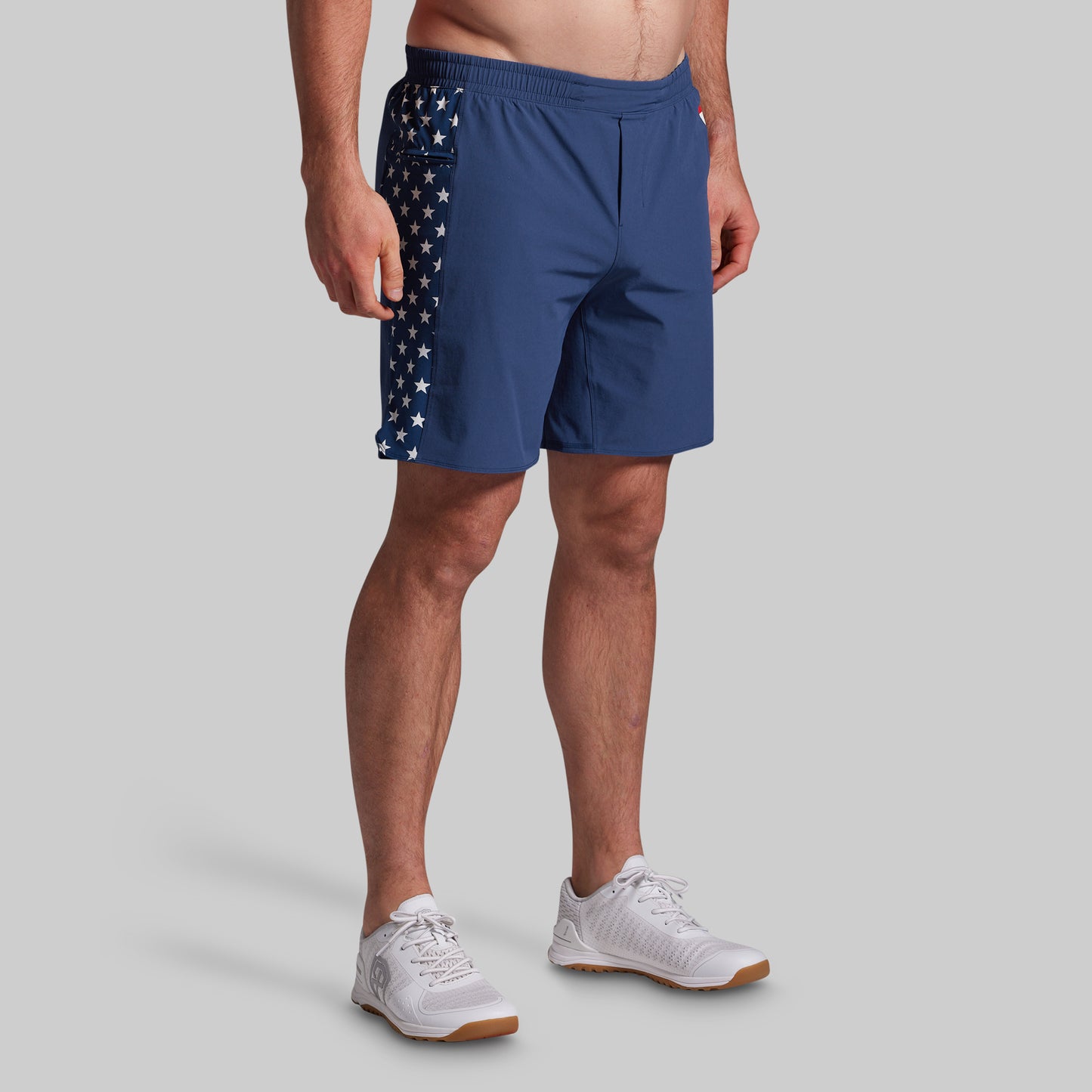 Person wearing blue athletic shorts with American flag design on a gray background