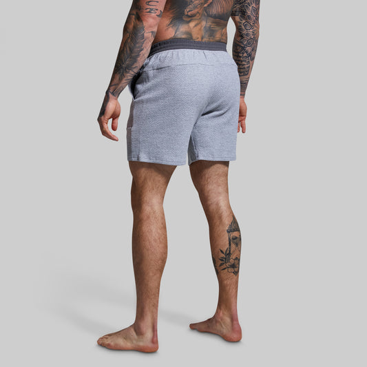 Person wearing gray textured shorts on a plain background