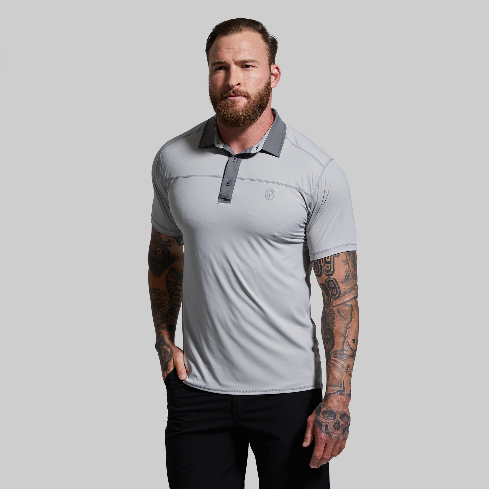 Man wearing a light gray polo shirt with a collar on a plain background