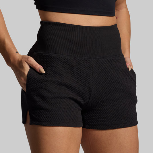 Person wearing black lounge shorts on a plain background