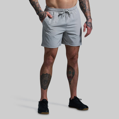 Person wearing light gray shorts on a plain background