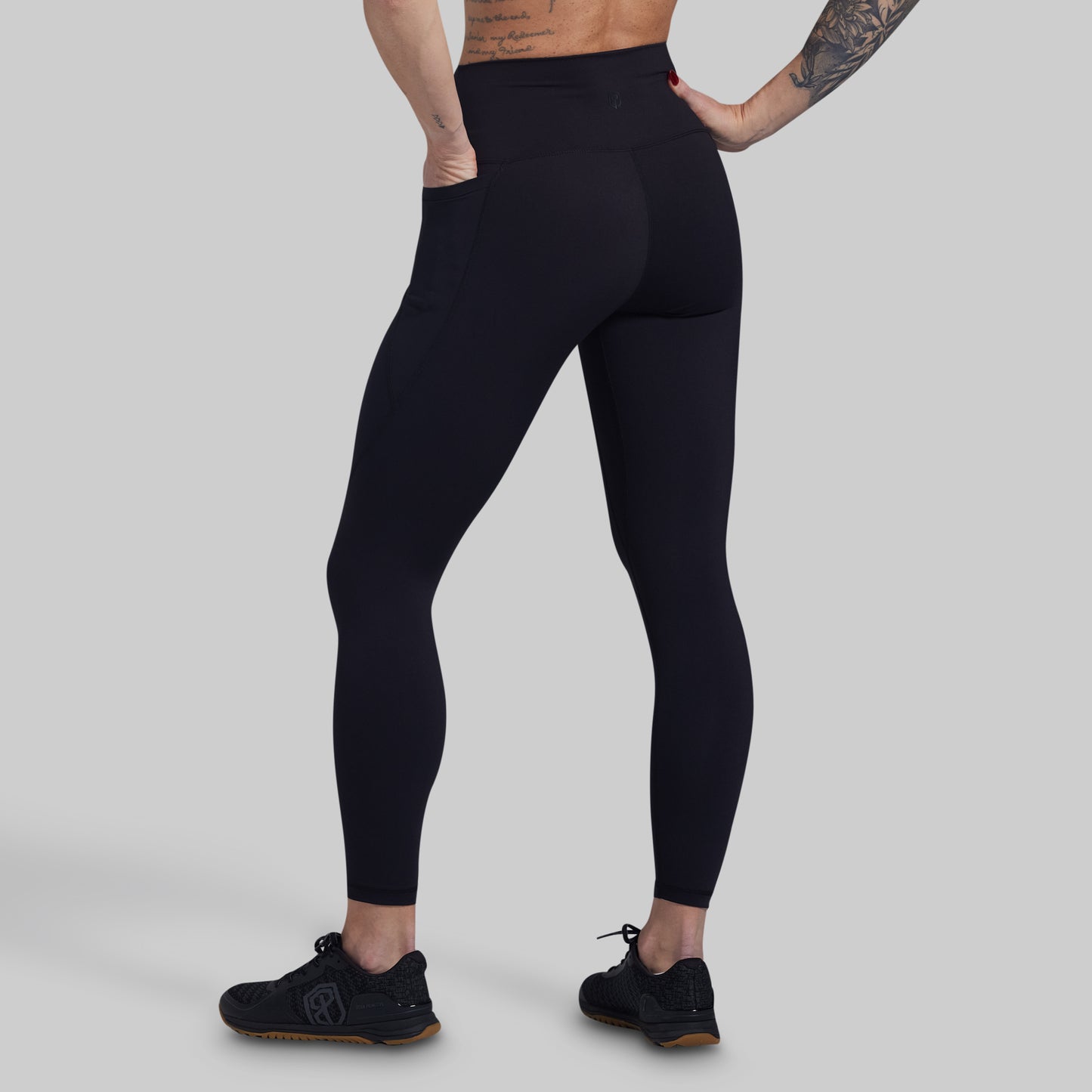 Person wearing black leggings on a gray background
