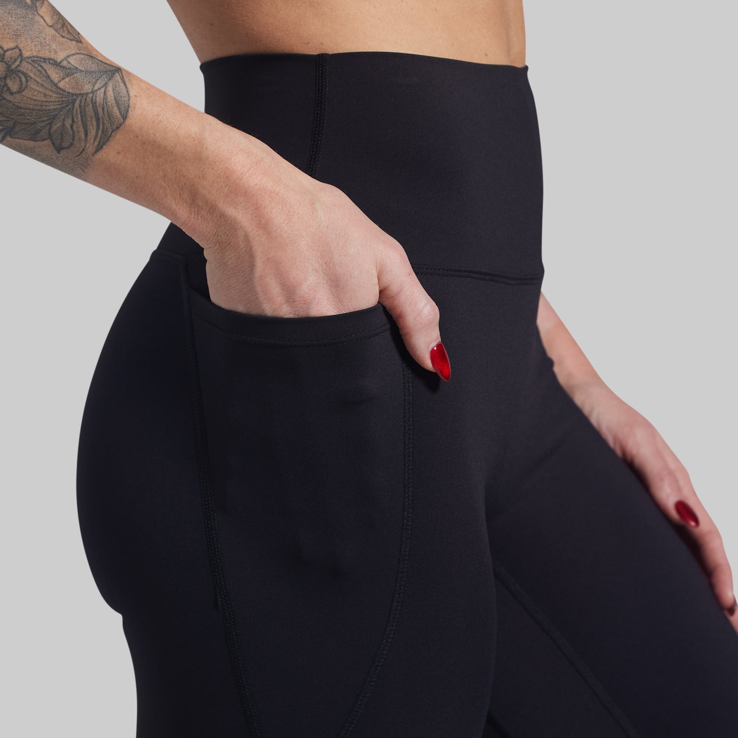 Person wearing black leggings with a plain background