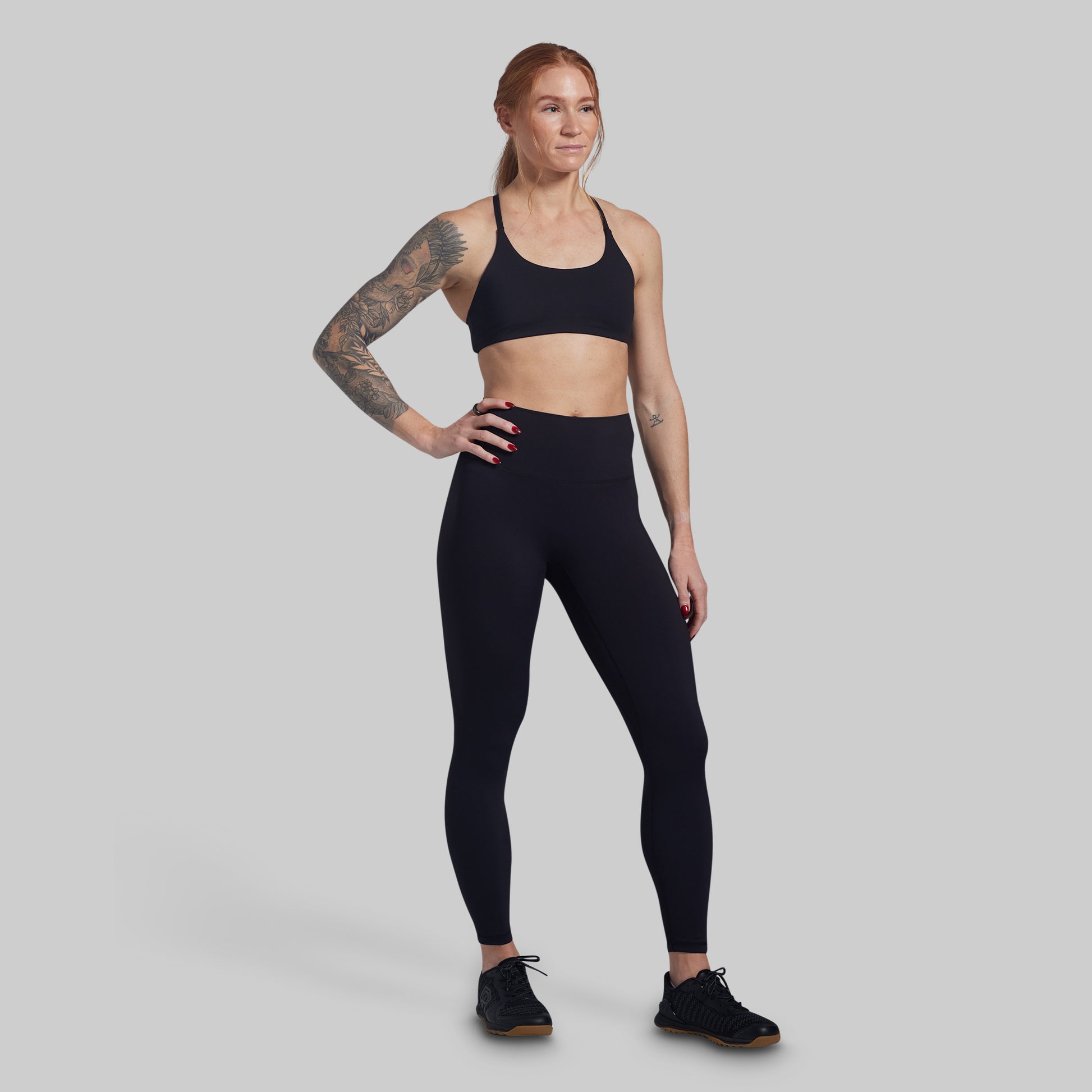Woman wearing black athletic wear on a gray background