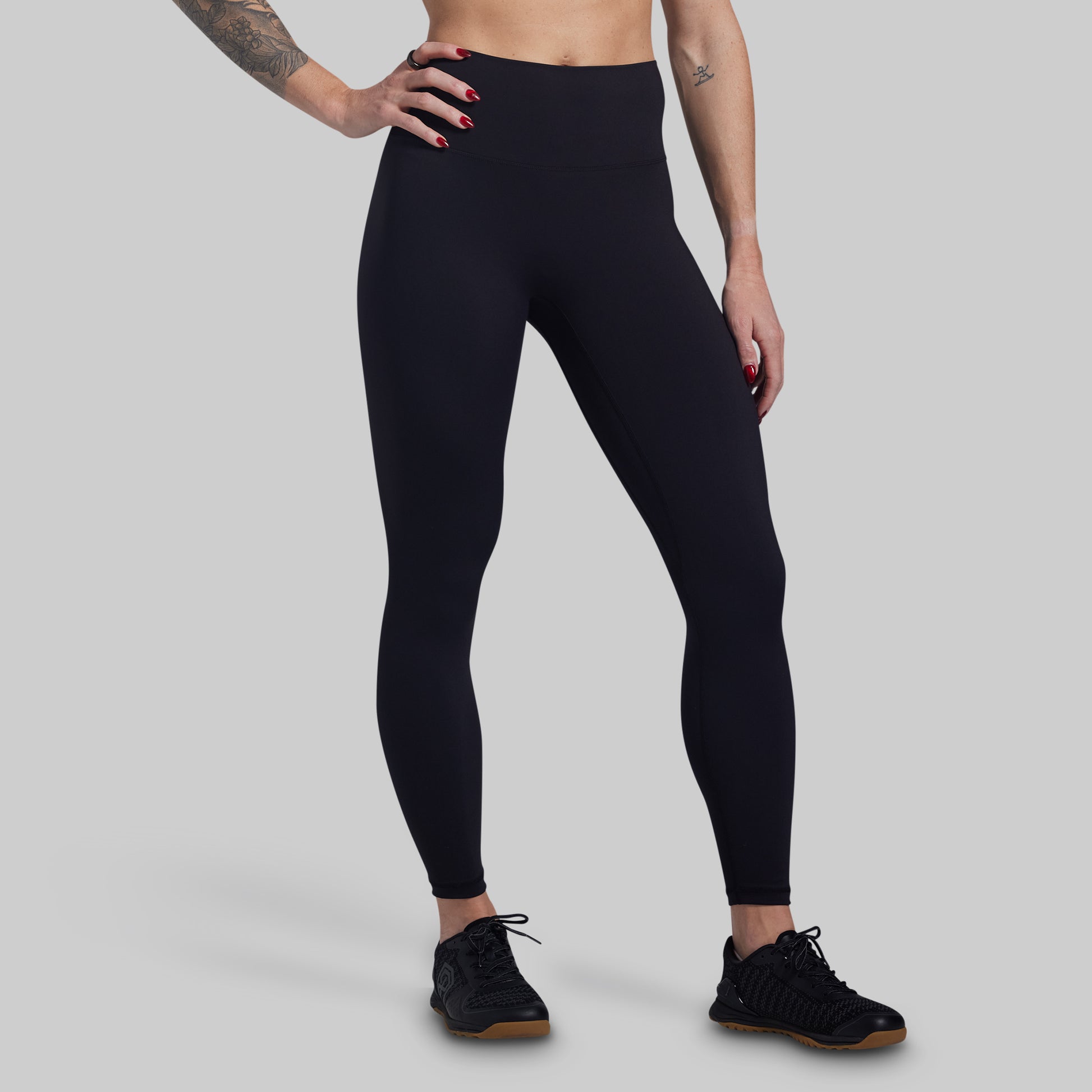 Person wearing black leggings on a gray background
