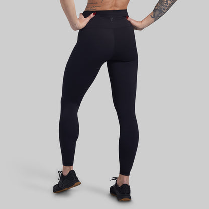 Person wearing black leggings on a gray background