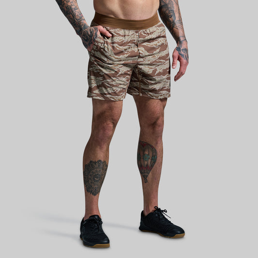 A person wearing camouflage patterned Versatile Shorts with a compression liner, standing against a plain background.