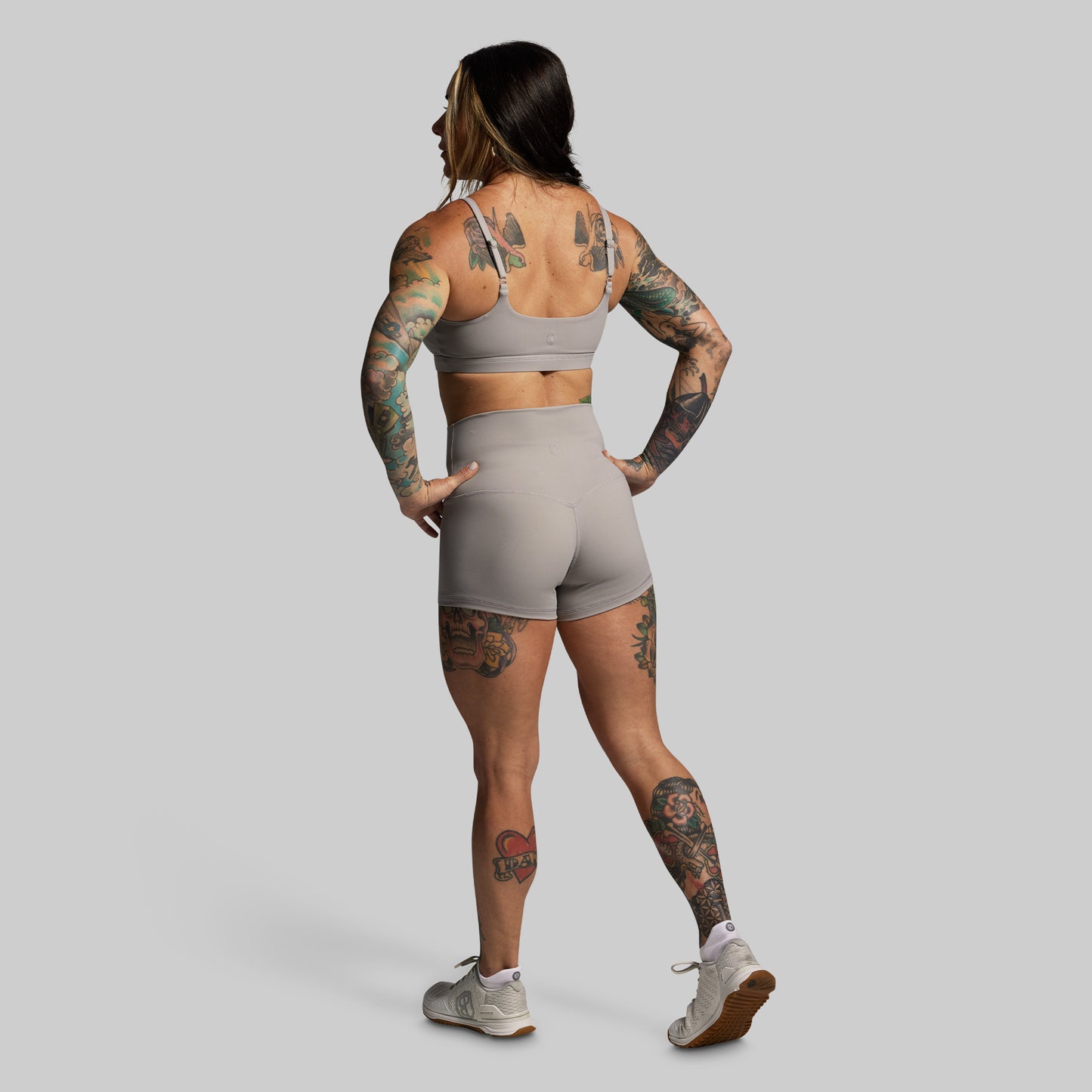 Person wearing a gray sports bra and shorts set on a plain background