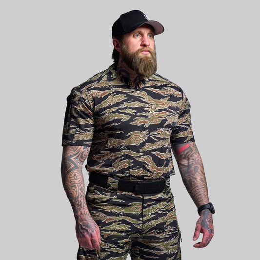 Man wearing a camouflage outfit with a black cap on a gray background