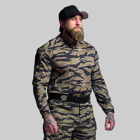 Man wearing a camouflage outfit with a black cap on a gray background