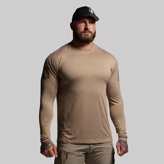 Man wearing a beige long-sleeve shirt and cap on a gray background