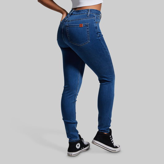 Person wearing blue jeans and black sneakers on a gray background
