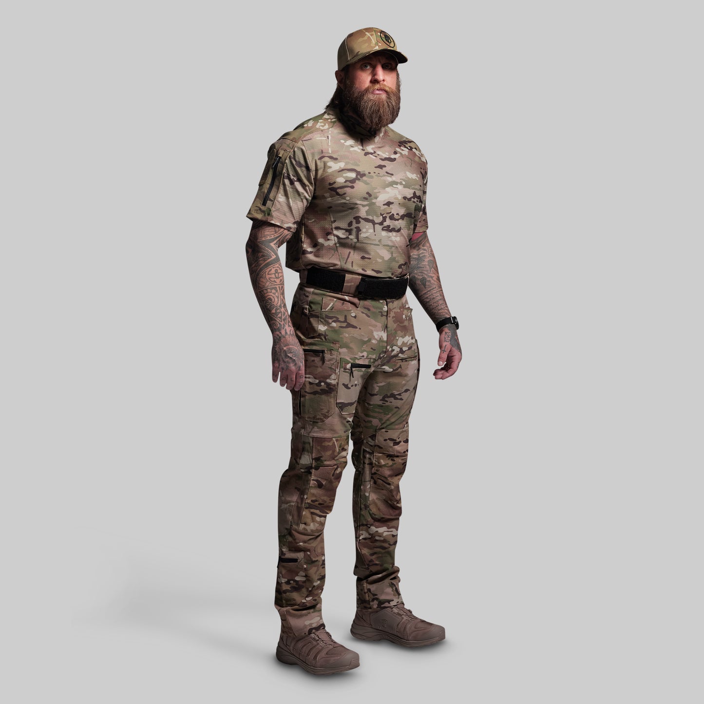 Person wearing a full camouflage outfit with a cap on a gray background