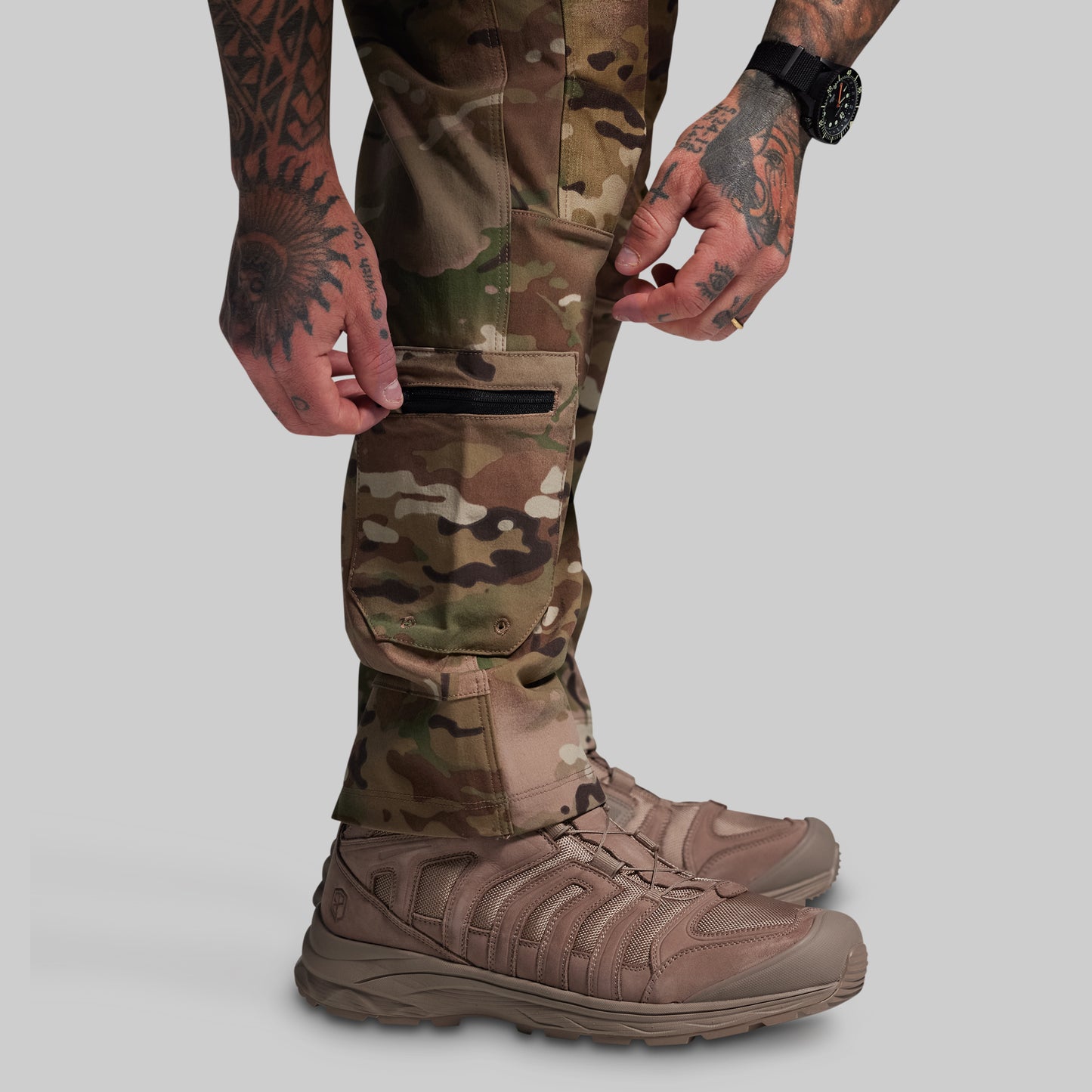 Person wearing camouflage pants and boots on a gray background