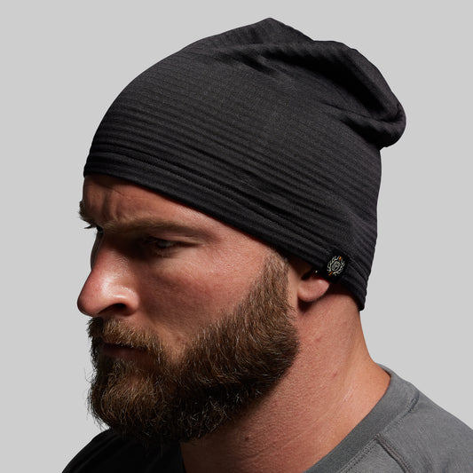 Man wearing a black beanie against a gray background