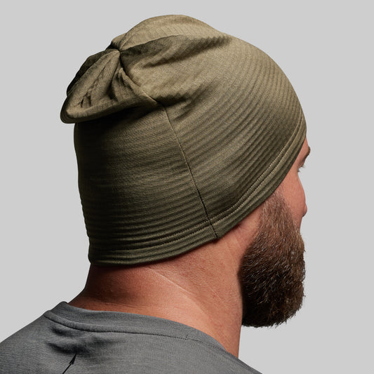 Person wearing a green beanie on a gray background