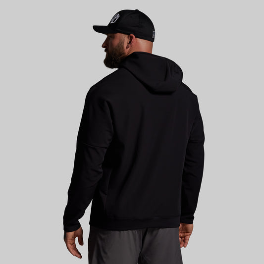 Man wearing a black hoodie and cap on a gray background